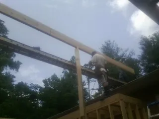 Carpenter setting a ridge beam over a new addition frame — Ice Dam Removal by Roofing Brothers in Firestone