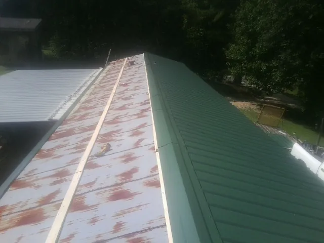Old rusted panels beside newly installed green metal roofing — Wind Damage Roof Repair by Roofing Brothers in Firestone