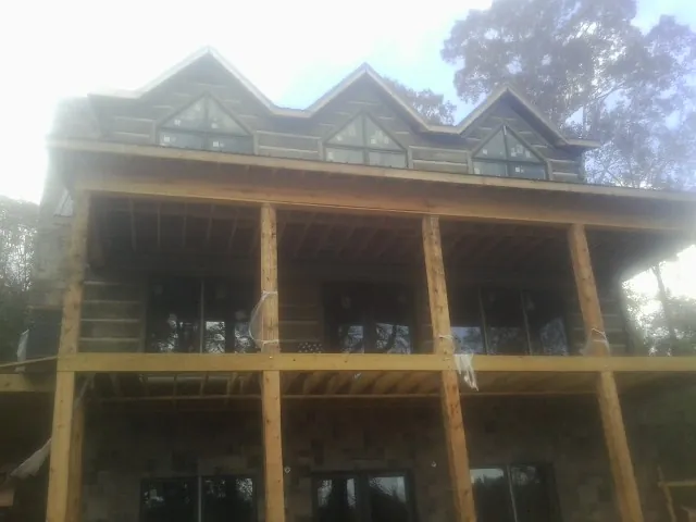 Dormers and porch framing on a large log home under construction — Roof Coating work by our crew in Firestone