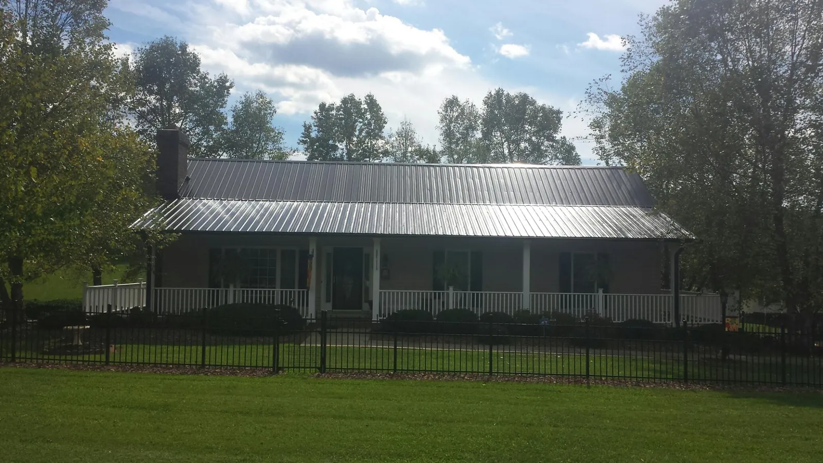 Gray metal roof on a brick ranch with a full width front porch — Gutter Guard Installation work by our crew in Firestone