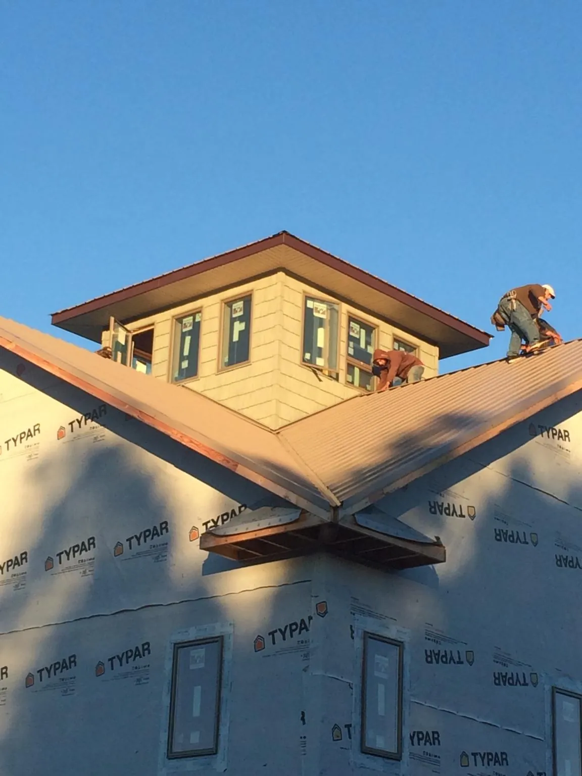 Roofers working around a rooftop cupola on a new metal roof at sunset — Roof Waterproofing in Firestone by Roofing Brothers